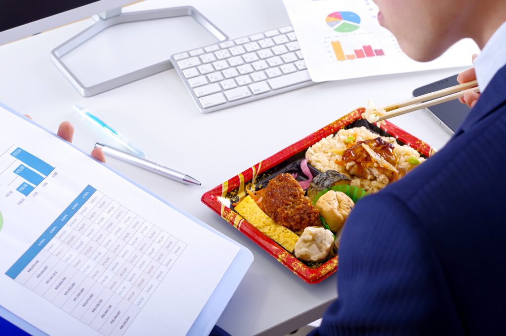 デスクでコンビニ弁当を食べるビジネスマン